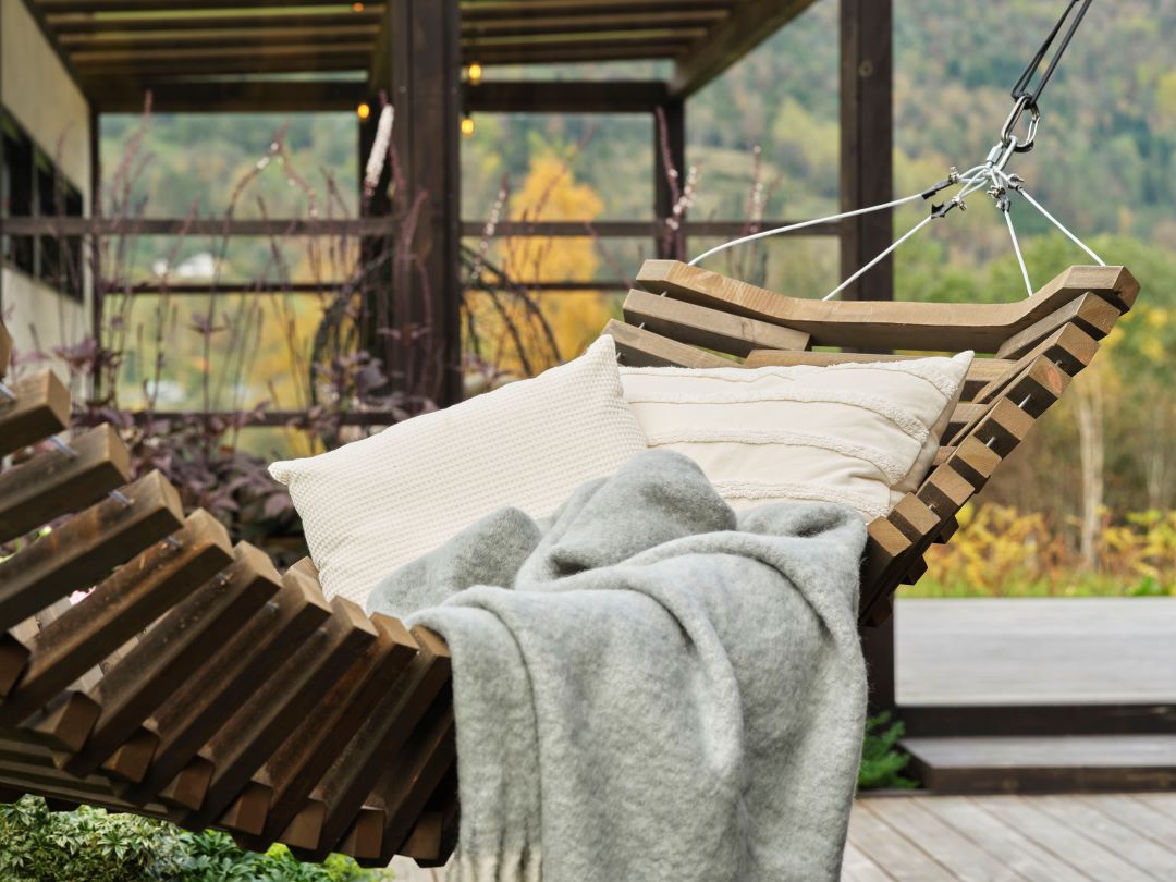 DIY: Hengekøye i MøreRoyal Foto fra Marte Helgetun sin hage - hengekøye i MøreRoyal grå i fokus. Utsnitt... I hengekøyen ligger det myke puter og pledd.